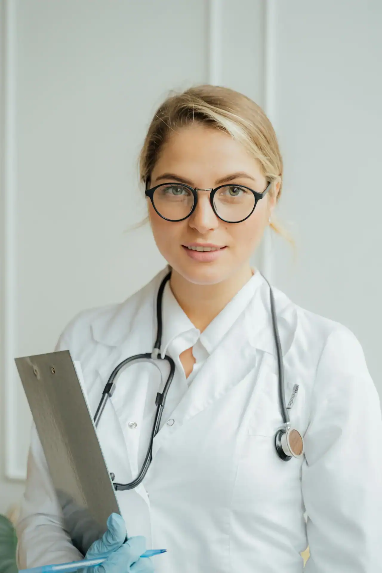 Radiology technician wearing glasses and a white lab coat with a stethoscope, holding a clipboard, representing mobile x-ray services and healthcare professionals at National Mobile X-Ray.